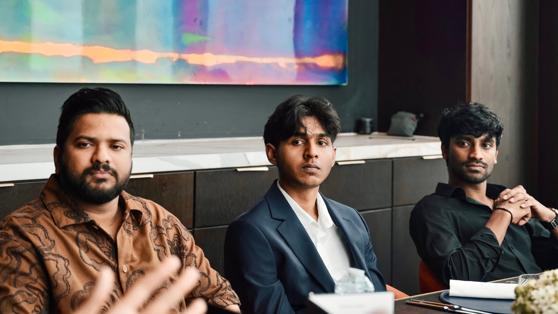 Three members seated together under the artwork at a meetup