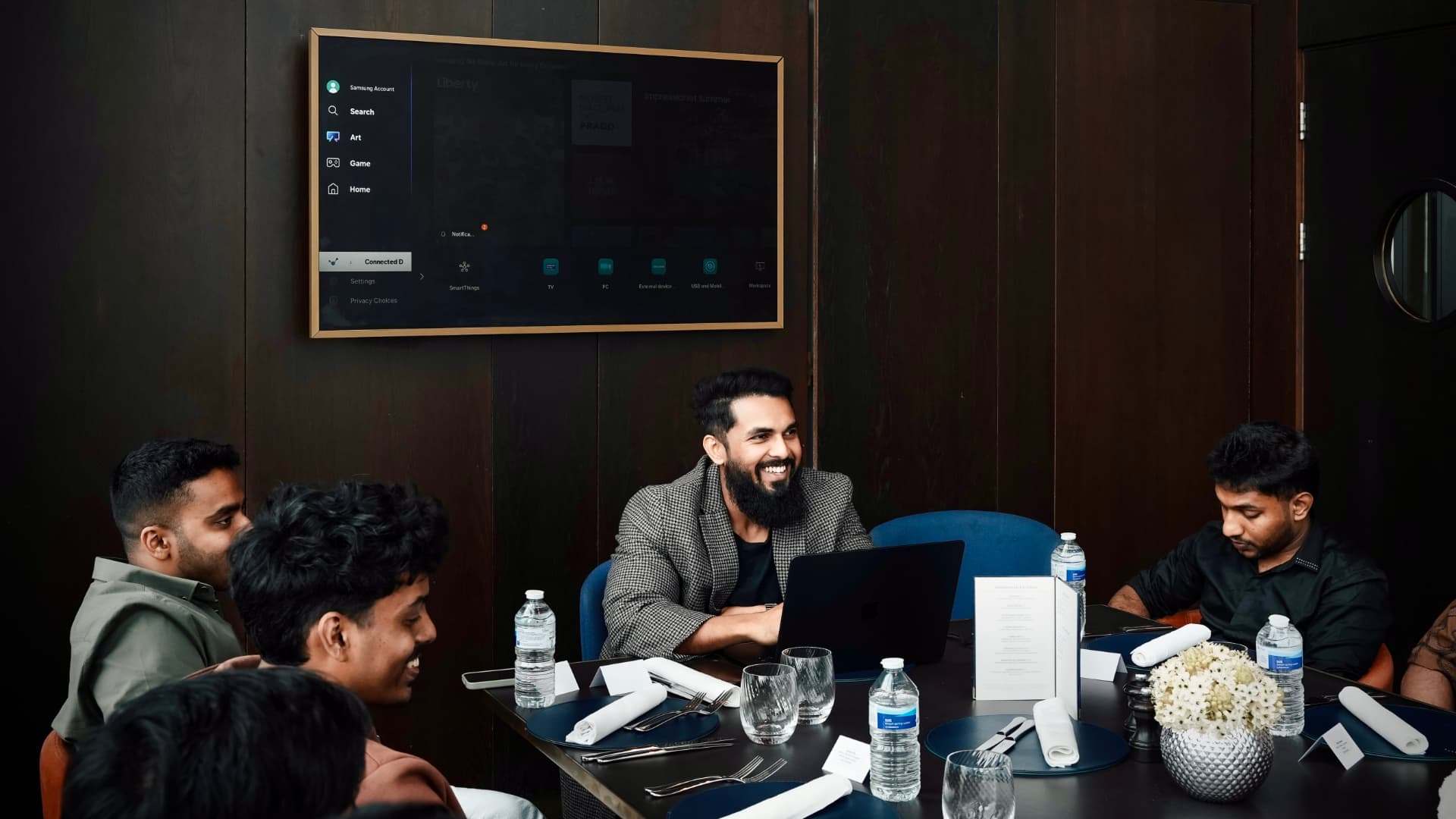 A member smiling over his laptop during a mastermind dinner