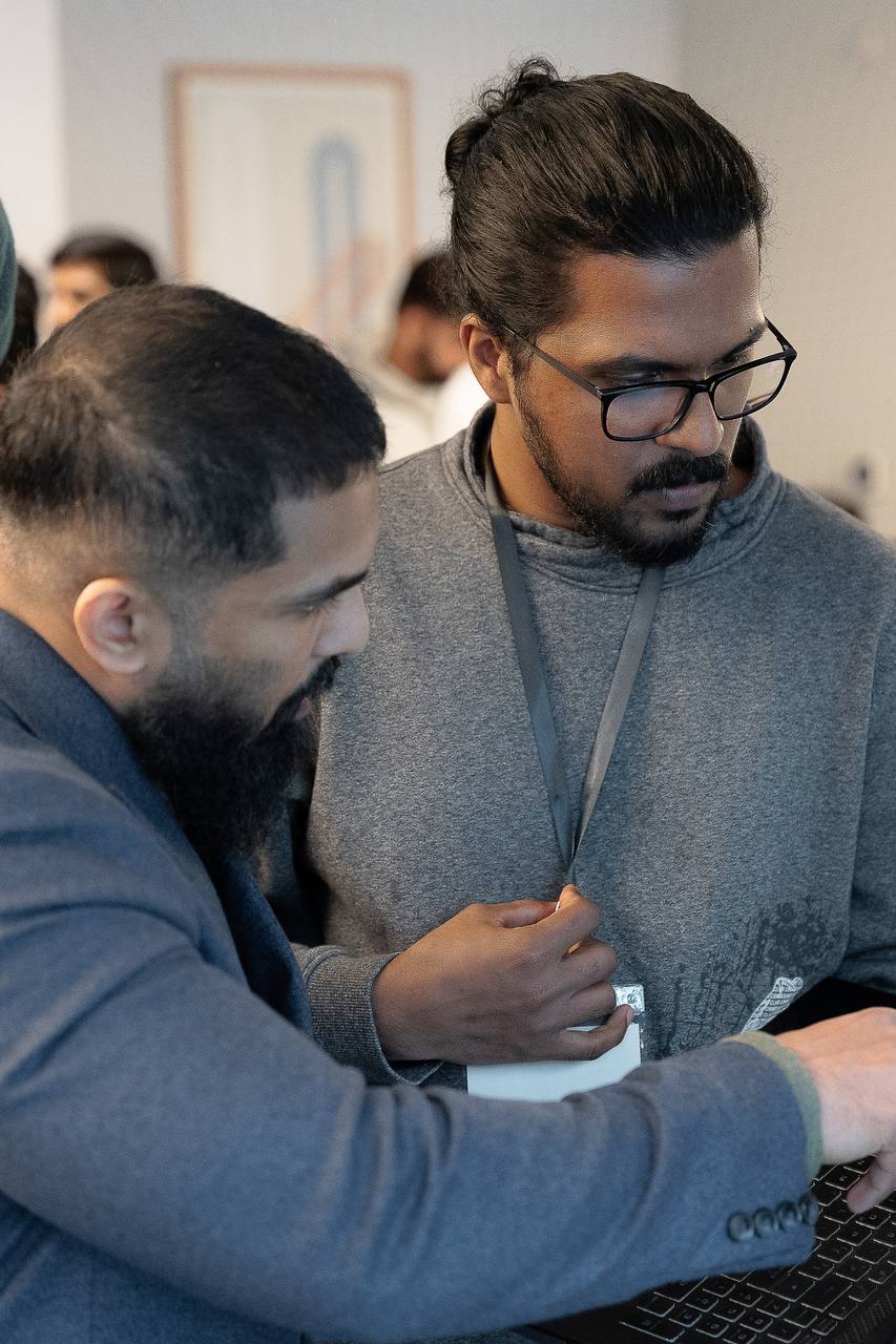 Two members working through a laptop together at a meetup