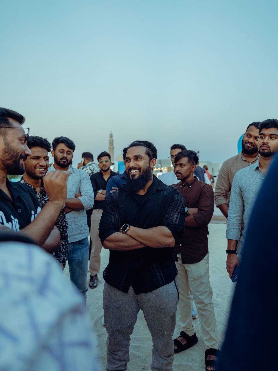 A member laughing with the group on the beach at sunset