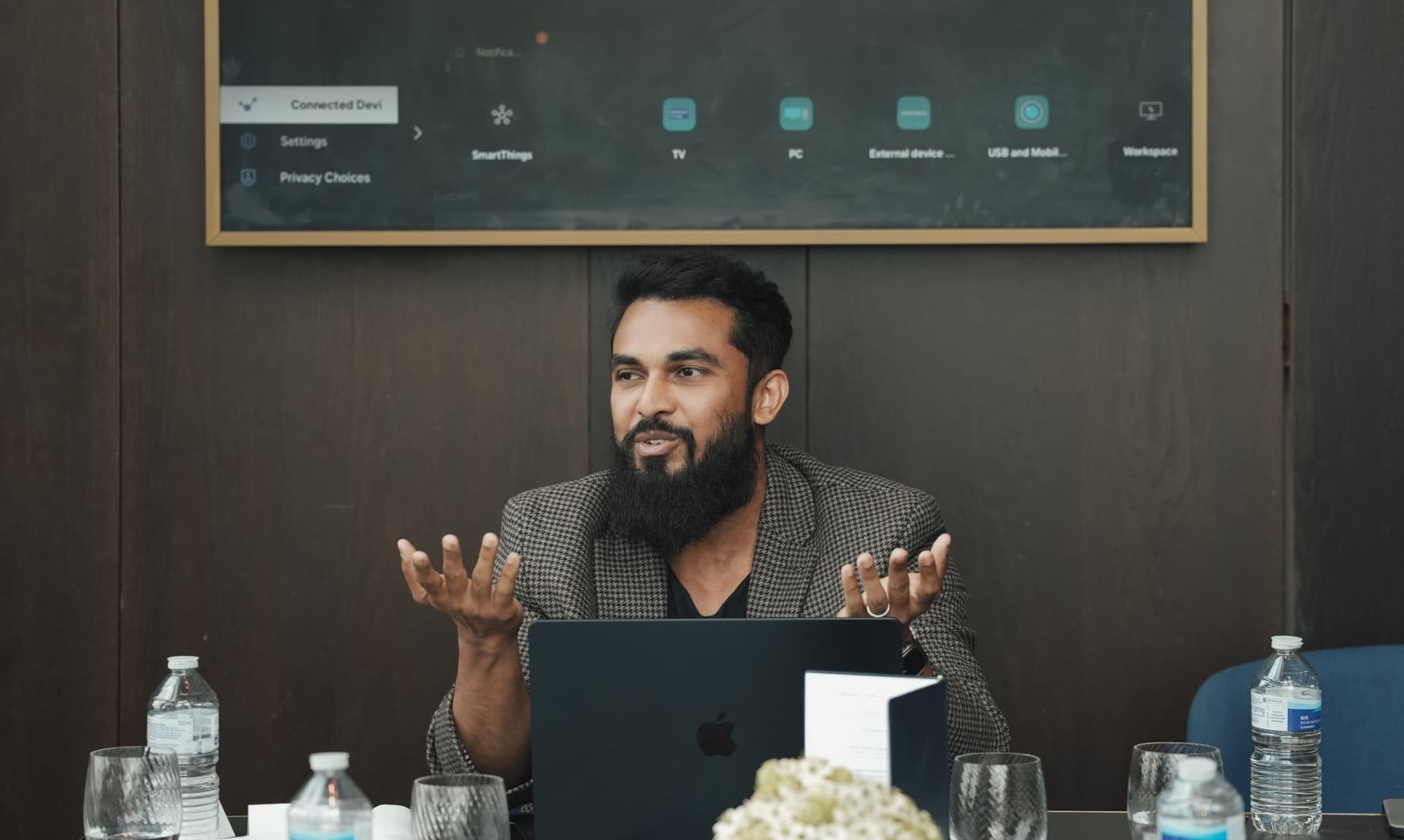 A member speaking with his laptop at the head of the table at a meetup